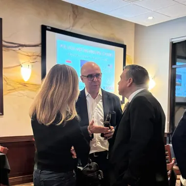 Three people talking beside a presentation screen during a break between sessions