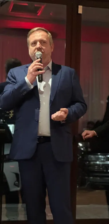 A speaker addressing the room with a handheld microphone at an evening event